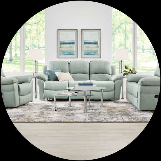 A living room set with a light green sofa, two armchairs, and a glass coffee table.
