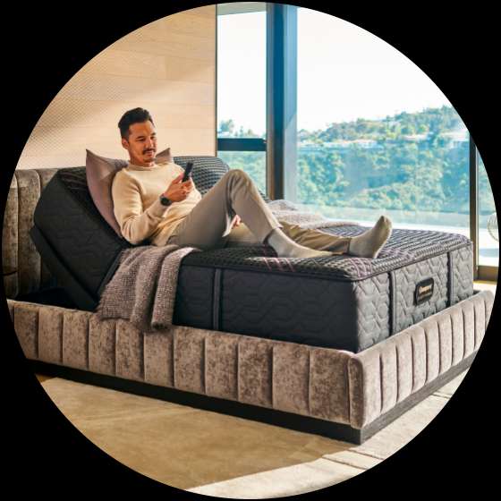 Man reclining on an adjustable bed, holding a remote.
