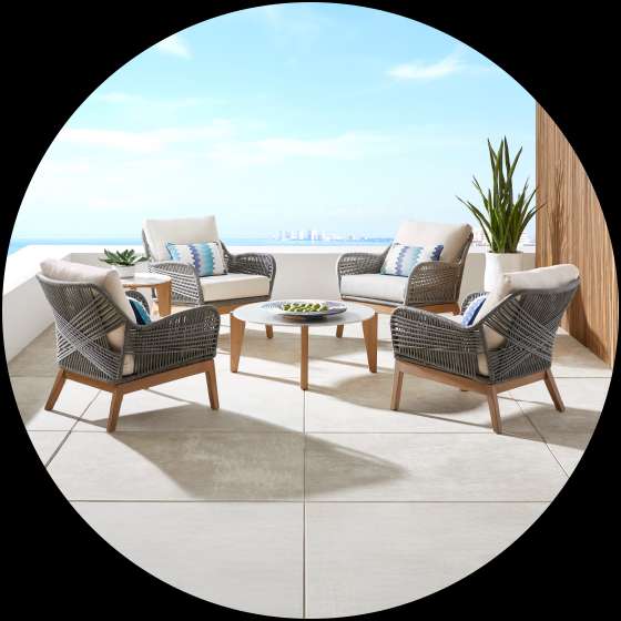 Outdoor furniture set on a patio overlooking the ocean.
