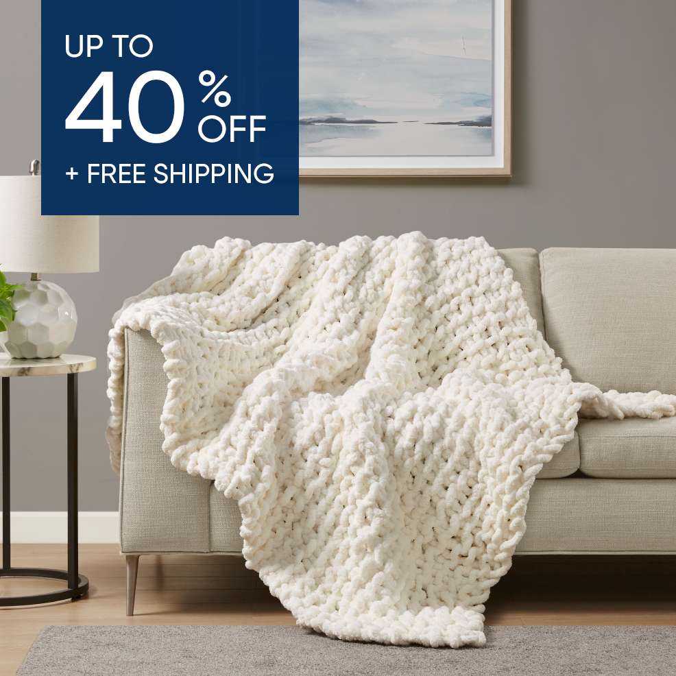 Up to 40% off + free shipping. A cream-colored chunky knit blanket draped over a beige sofa.
