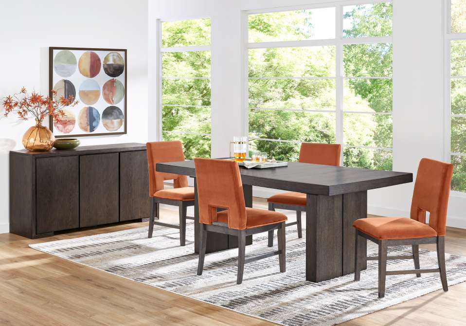 Dining room set with a dark wood table, orange chairs, and a matching sideboard.
