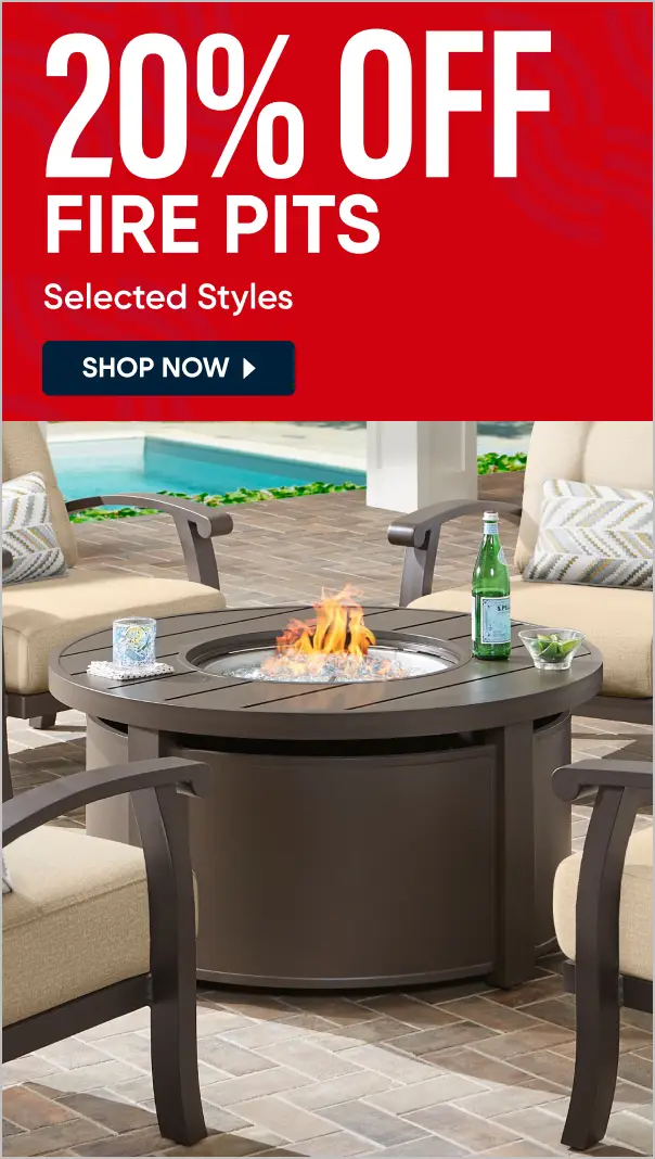 20% OFF FIRE PITS Selected Styles. A round, dark brown outdoor fire pit table with a lit fire, surrounded by patio chairs.