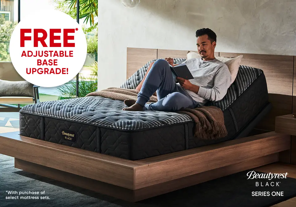 FREE ADJUSTABLE BASE UPGRADE! Beautyrest Black Series One mattress on an adjustable base with a man reading in bed.