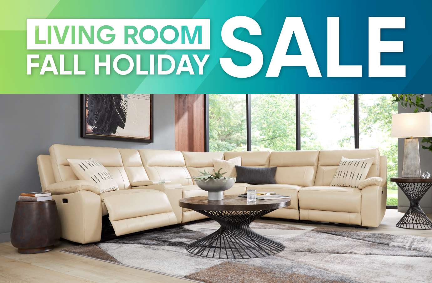 LIVING ROOM FALL HOLIDAY SALE. A beige sectional sofa with pillows, a coffee table, and a rug.
