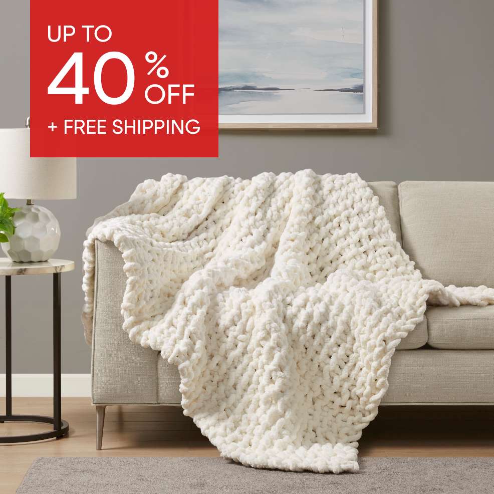 Up to 40% off + Free Shipping. A chunky knit cream-colored blanket draped over a beige couch.