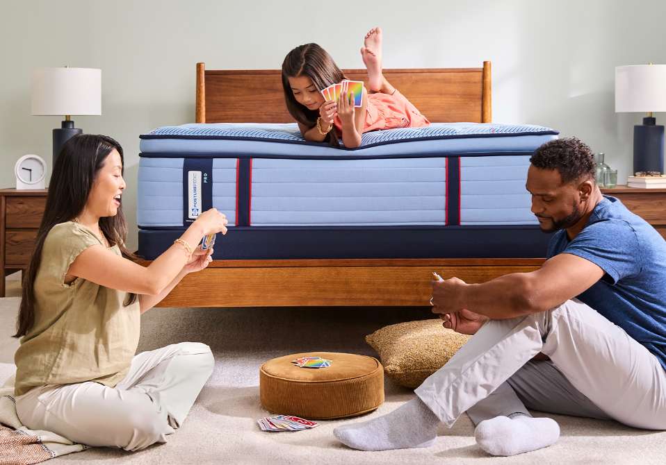 A family plays cards on a bed.
