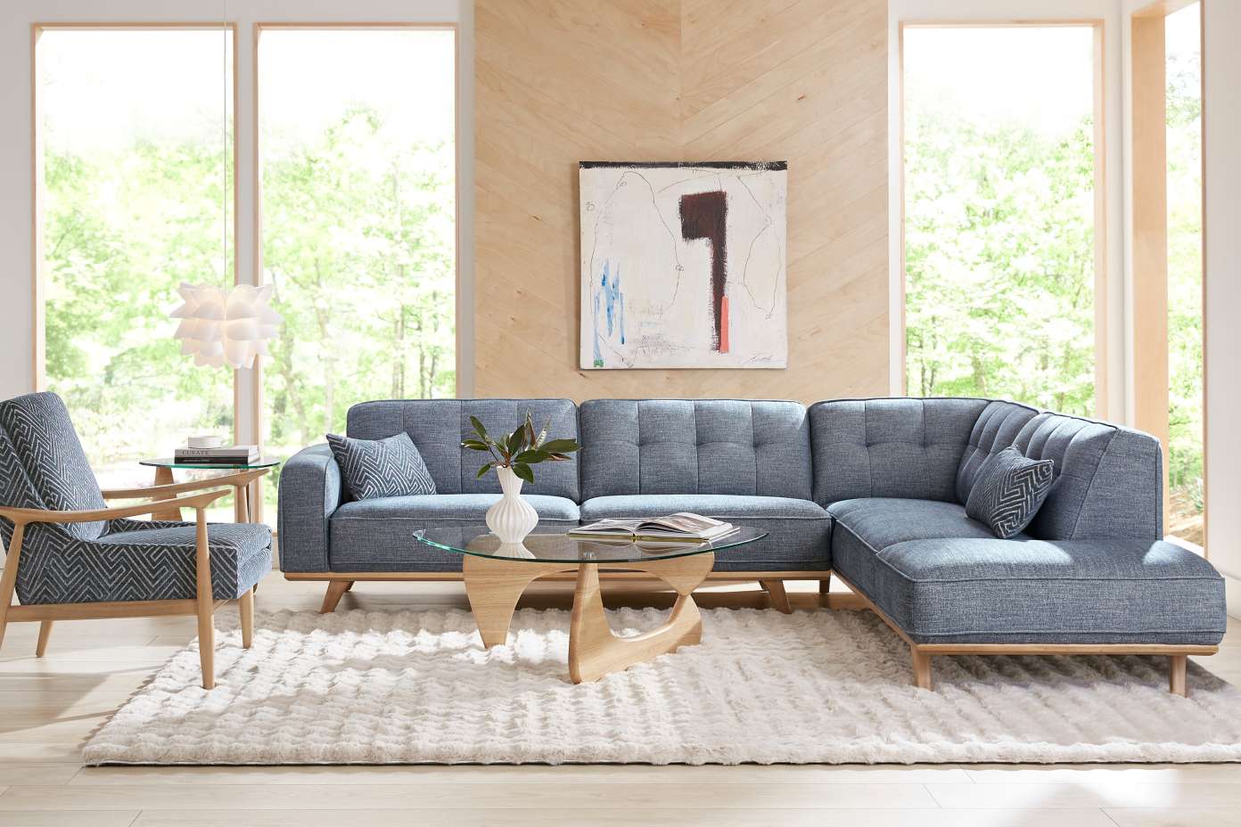 Blue sectional sofa with wooden frame, accent chair, and glass coffee table.
