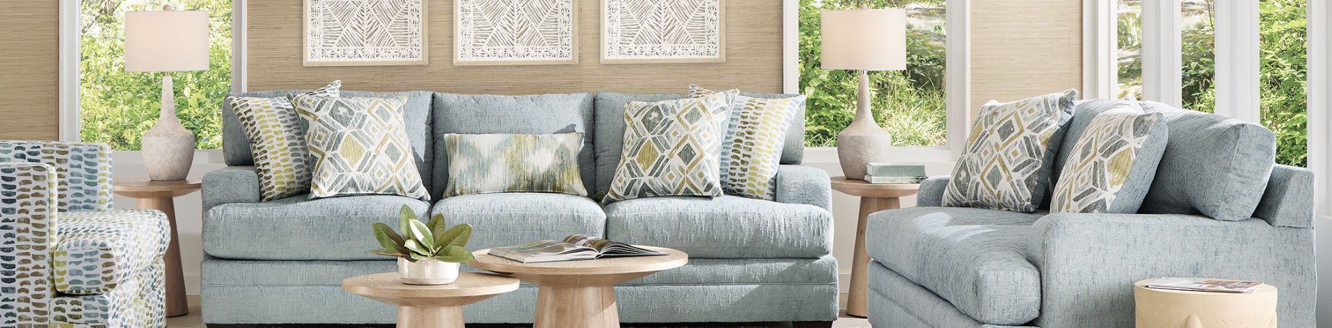 Blue sofa with patterned pillows and wooden side tables.