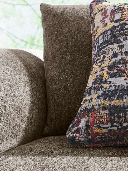 Close-up of a sofa with textured brown cushions and a patterned pillow.
