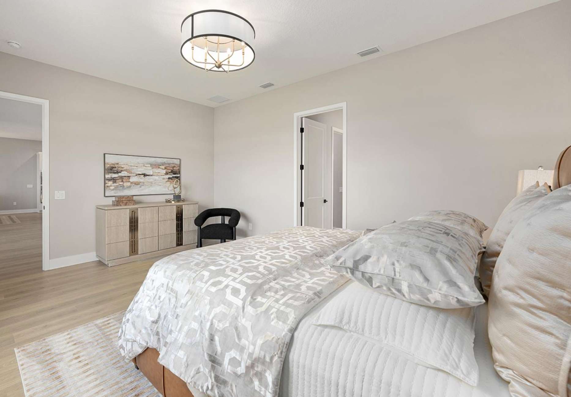 Bedroom with a bed, dresser, and a black chair.
