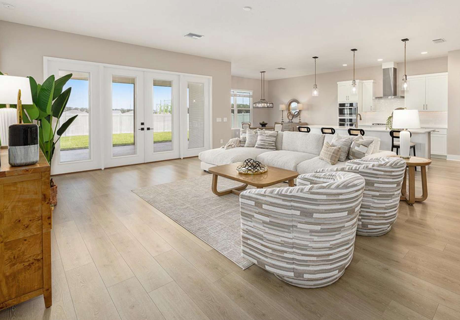 Living room with white sectional sofa, patterned armchairs, and wooden floor.
