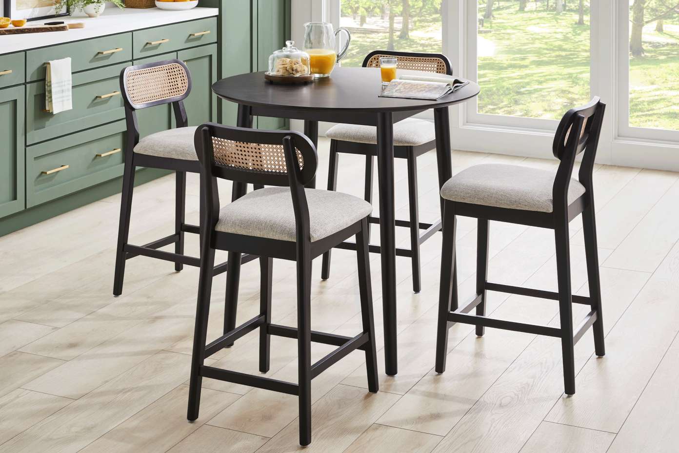 A black round dining table with four bar stools. The stools have woven backs and gray seats.
