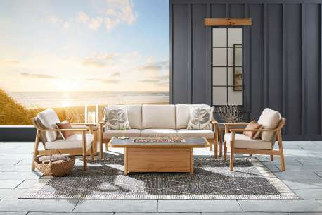 Outdoor furniture set with a sofa, two chairs, and a fire pit on a rug.
