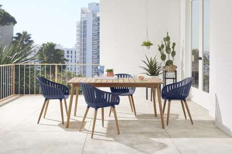 An outdoor dining set with a wooden table and blue chairs on a balcony.
