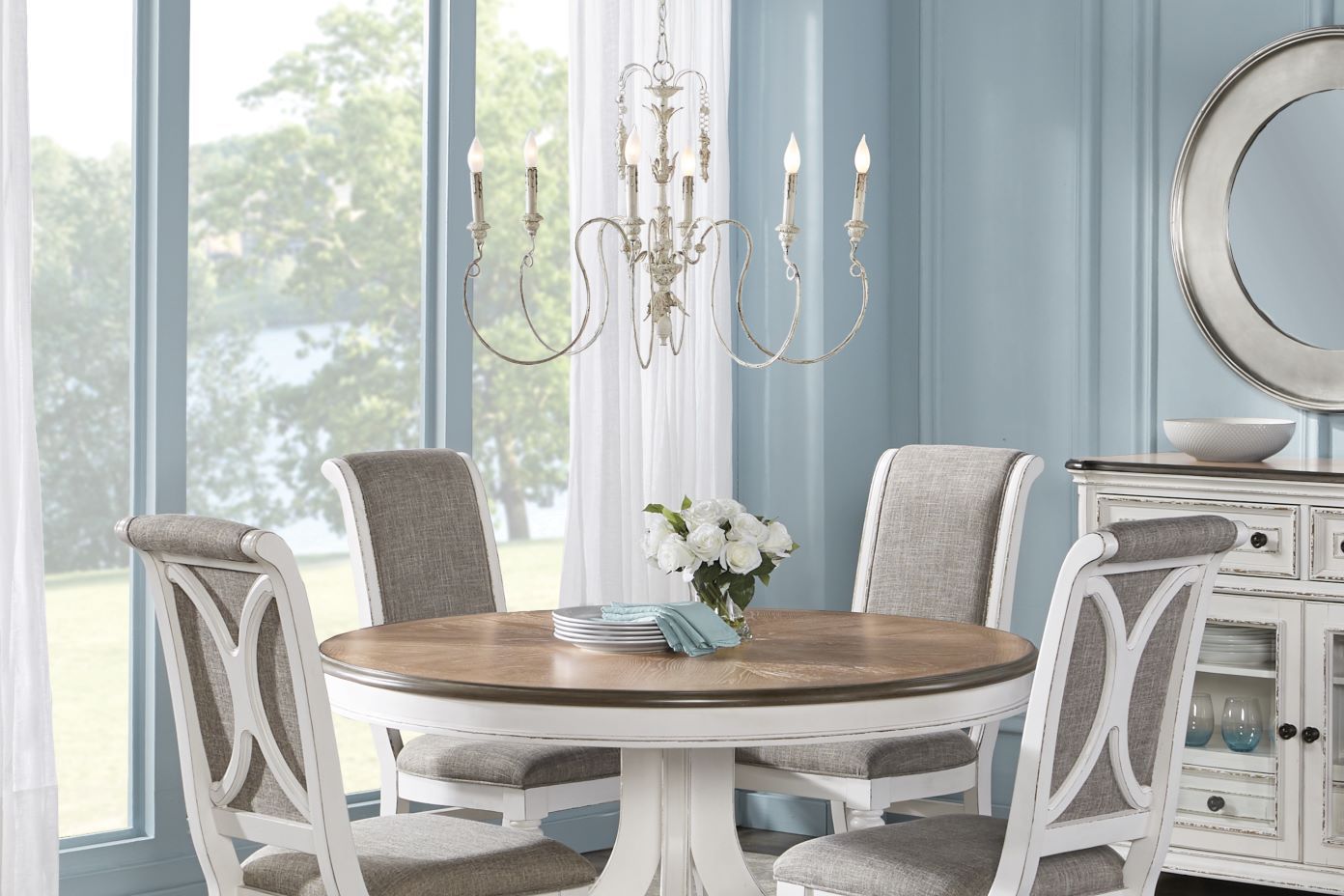 Dining room set with a round table, chairs, and chandelier.
