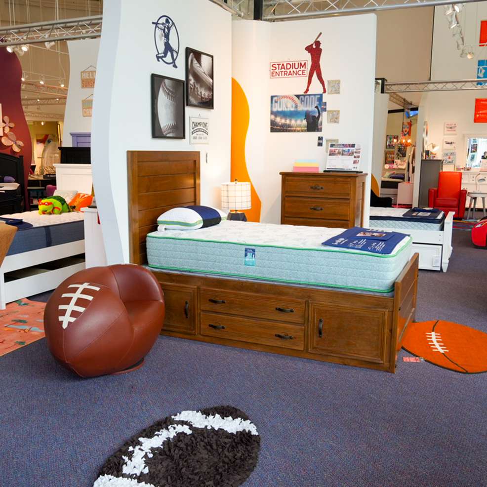 A bedroom set with a football theme, including a bed, chair, and rugs.
