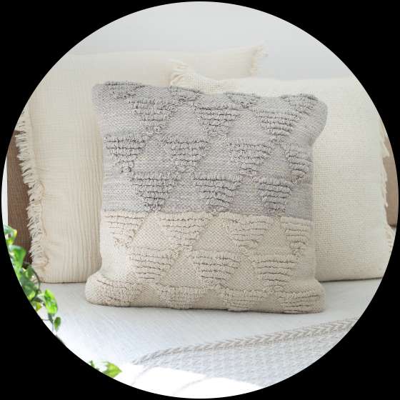 A decorative pillow with a geometric pattern, in shades of gray and cream.
