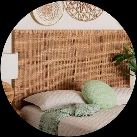 Rattan headboard with a bed, pillows, and a green throw.
