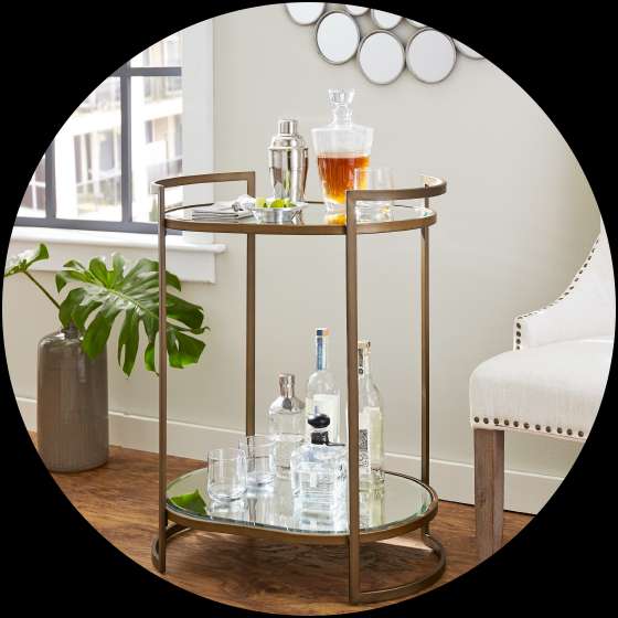 Bar cart with liquor bottles, glasses, and a decanter.
