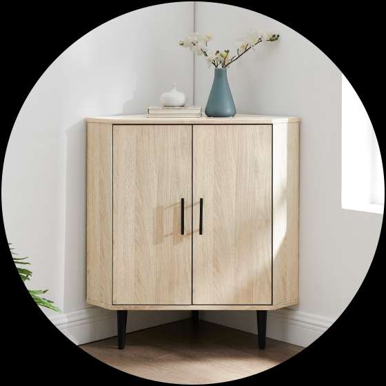A light wood corner cabinet with black handles and legs, topped with a vase and flowers.
