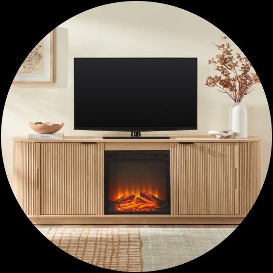 A light wood TV stand with a built-in fireplace and a TV on top.
