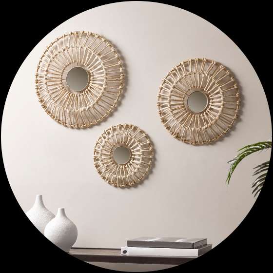 Three woven circular mirrors on a wall above a table with vases and books.
