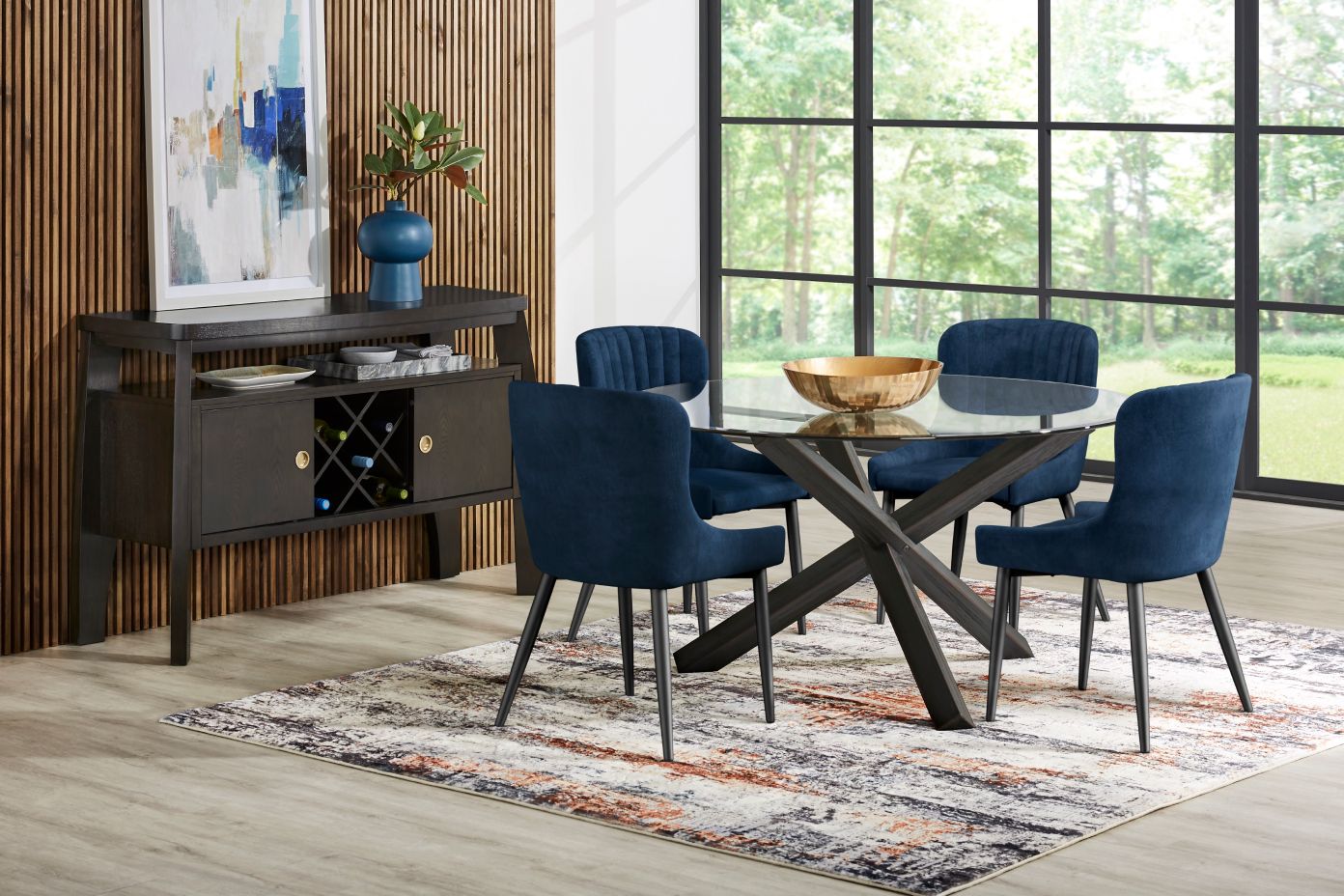 Dining room set with a glass table, blue chairs, and a dark wood sideboard.
