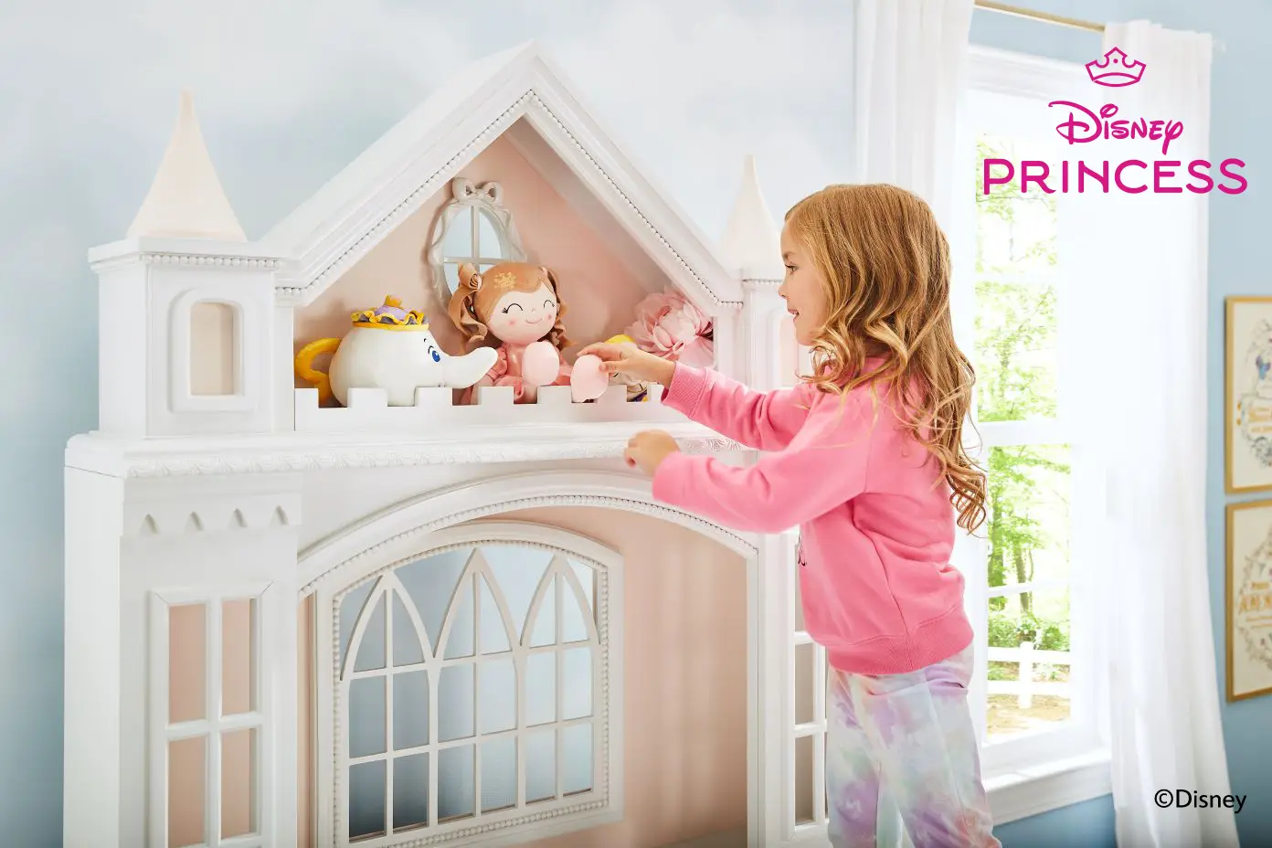 Disney Princess logo. A young girl plays with a dollhouse.
