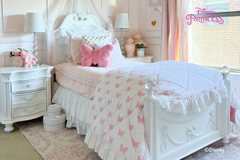Disney Princess bedroom with a white bed, pink butterfly bedding, and a canopy.
