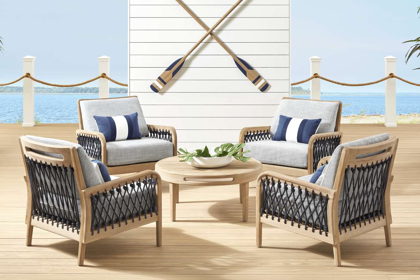 Outdoor furniture set with four chairs, a round table, and decorative oars.
