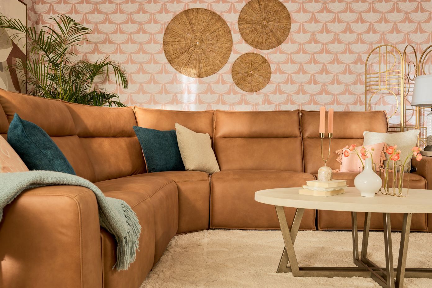 A brown leather sectional sofa with decorative pillows and a round coffee table.
