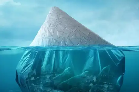 An iceberg made of plastic bags, with plastic waste visible underwater.
