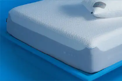 White mattress with a pillow on a blue surface.
