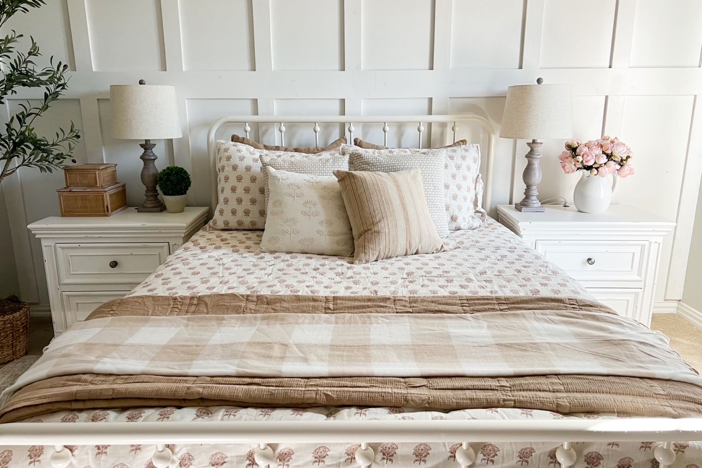 A bed with white nightstands, lamps, and decorative pillows.
