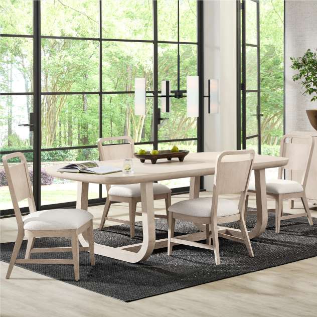 Dining room set with a light-colored wooden table and chairs, and a black rug.
