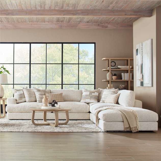 A sectional sofa in a neutral color with decorative pillows and a throw blanket.
