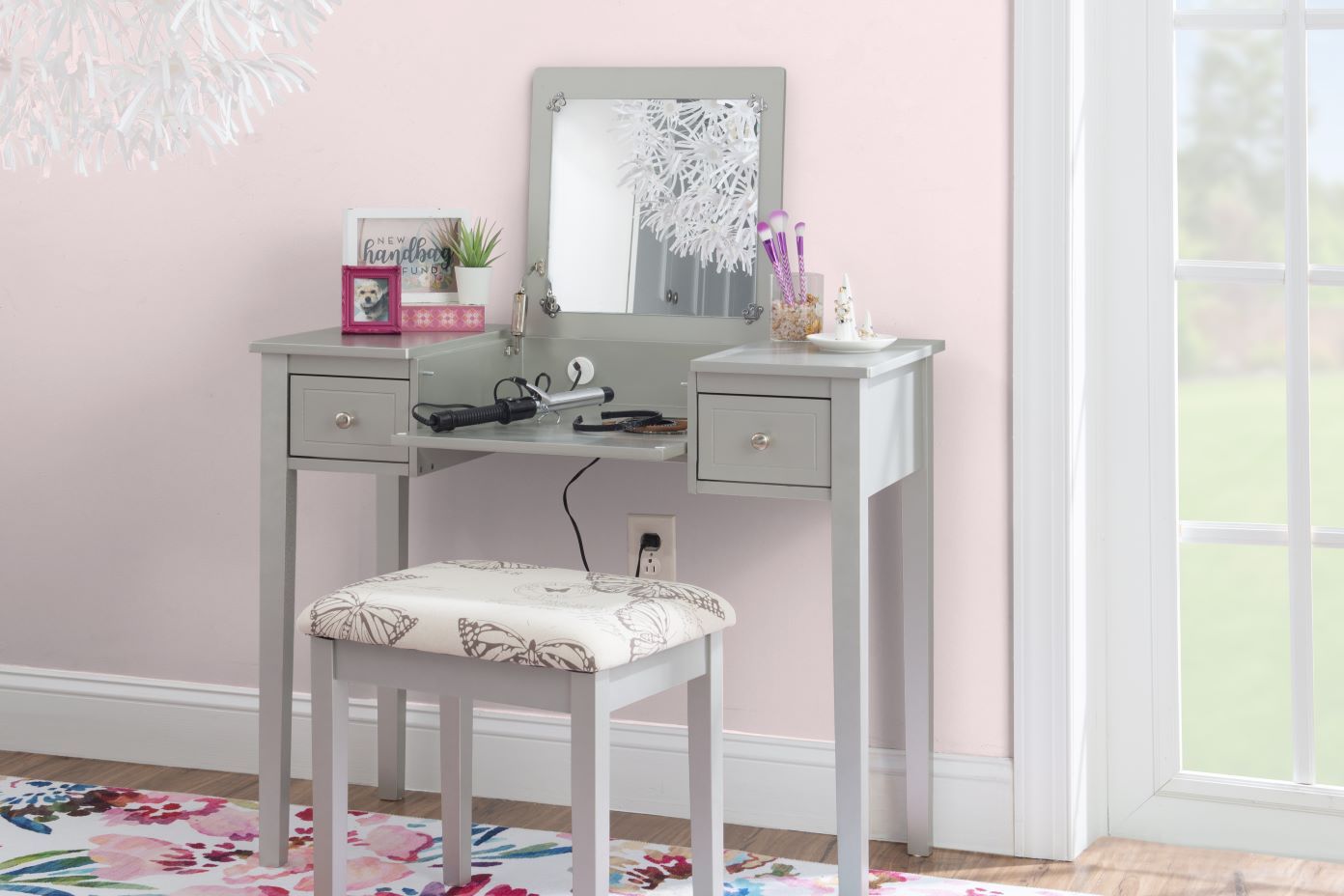Gray vanity table with a mirror, stool, and accessories.
