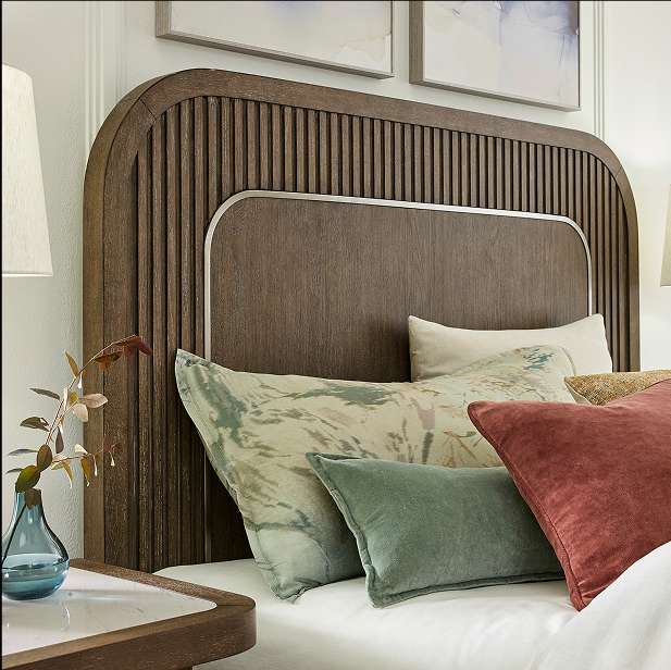 Wooden headboard with a silver trim and decorative pillows.
