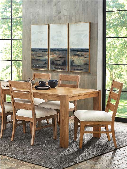 Wooden dining table and chairs with artwork on the wall.
