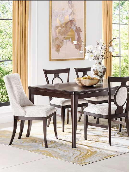 Dining room set with a dark wood table, chairs, and a patterned rug.
