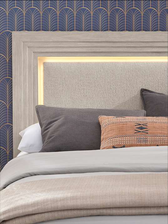 Bed with a gray headboard, pillows, and bedding.
