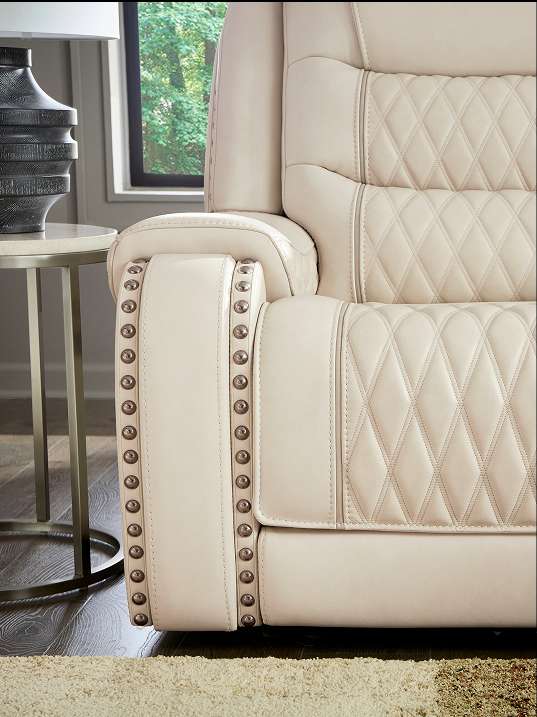 Cream-colored leather recliner with diamond stitching and studded armrests.
