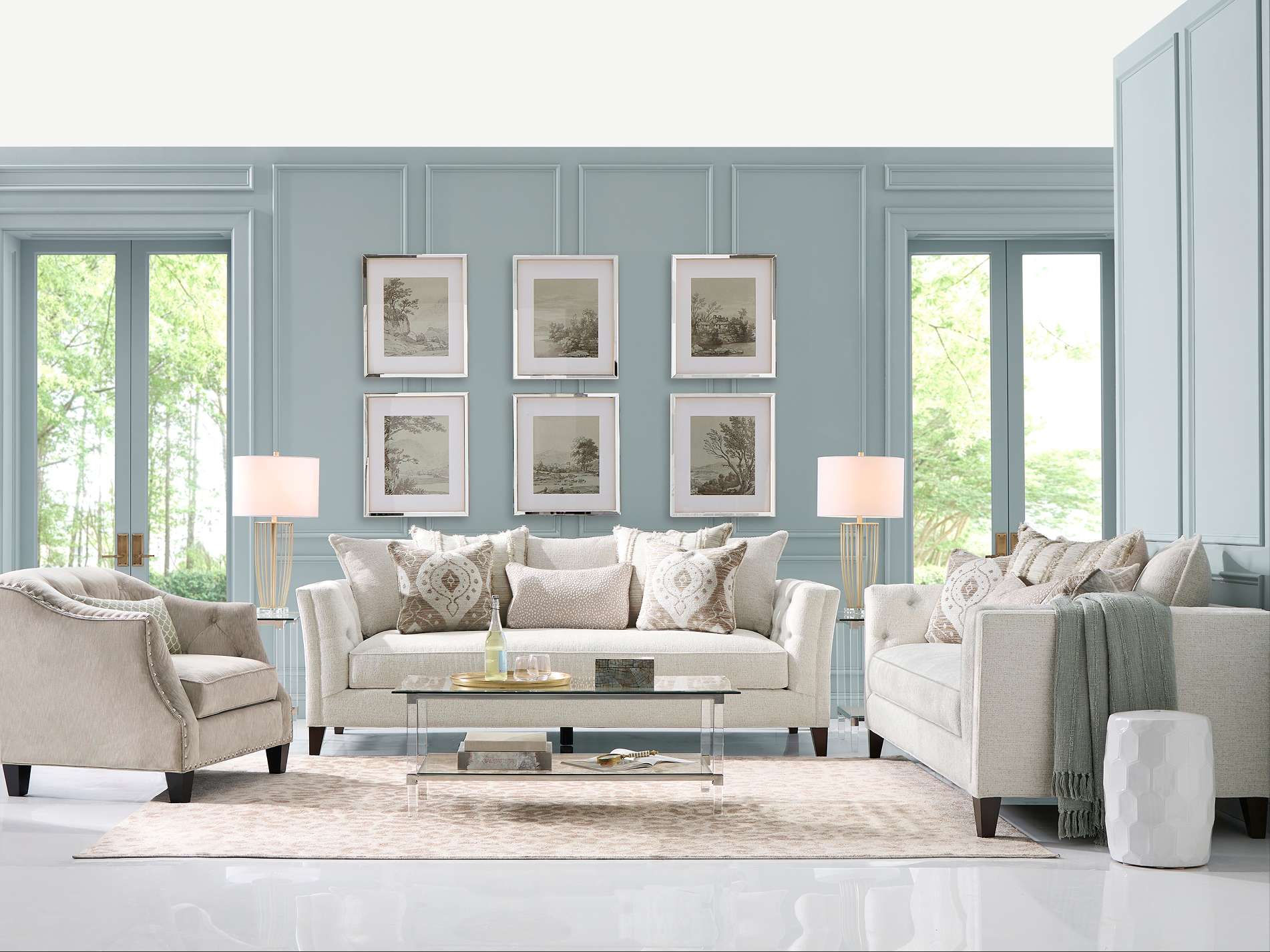 Living room with a light-colored sofa, armchair, and coffee table. There are framed pictures on the wall.
