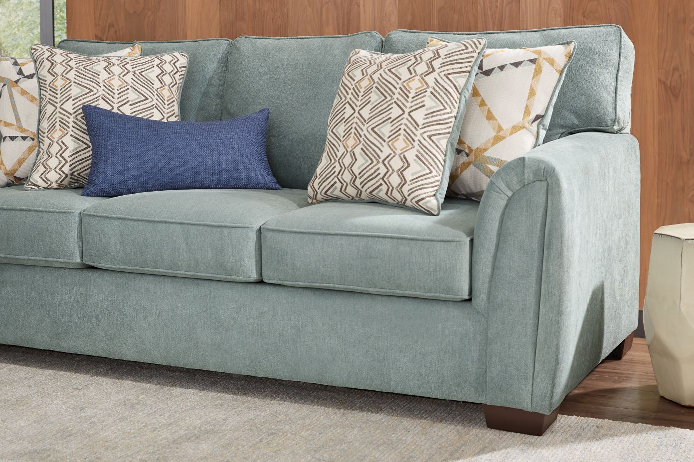 A light blue sofa with patterned pillows.
