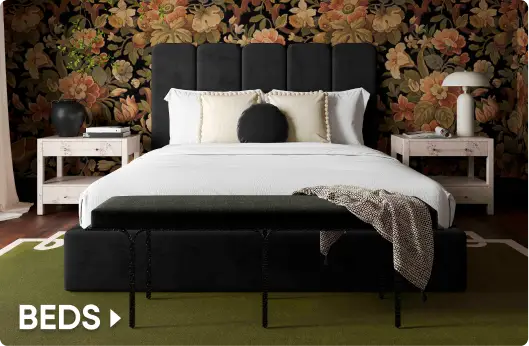 BEDS. A modern black upholstered bed with a channel-tufted headboard in a bedroom with floral wallpaper.