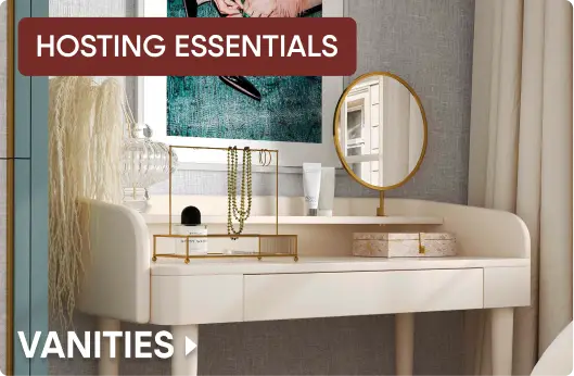 HOSTING ESSENTIALS VANITIES. A modern cream-colored vanity table with a gold jewelry stand, mirror, and accessories.