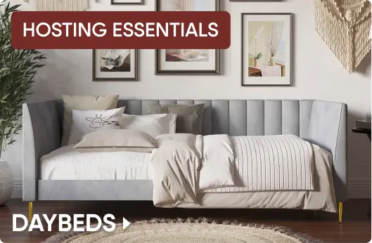 HOSTING ESSENTIALS DAYBEDS. A light grey upholstered daybed with gold legs, styled with neutral bedding and pillows.