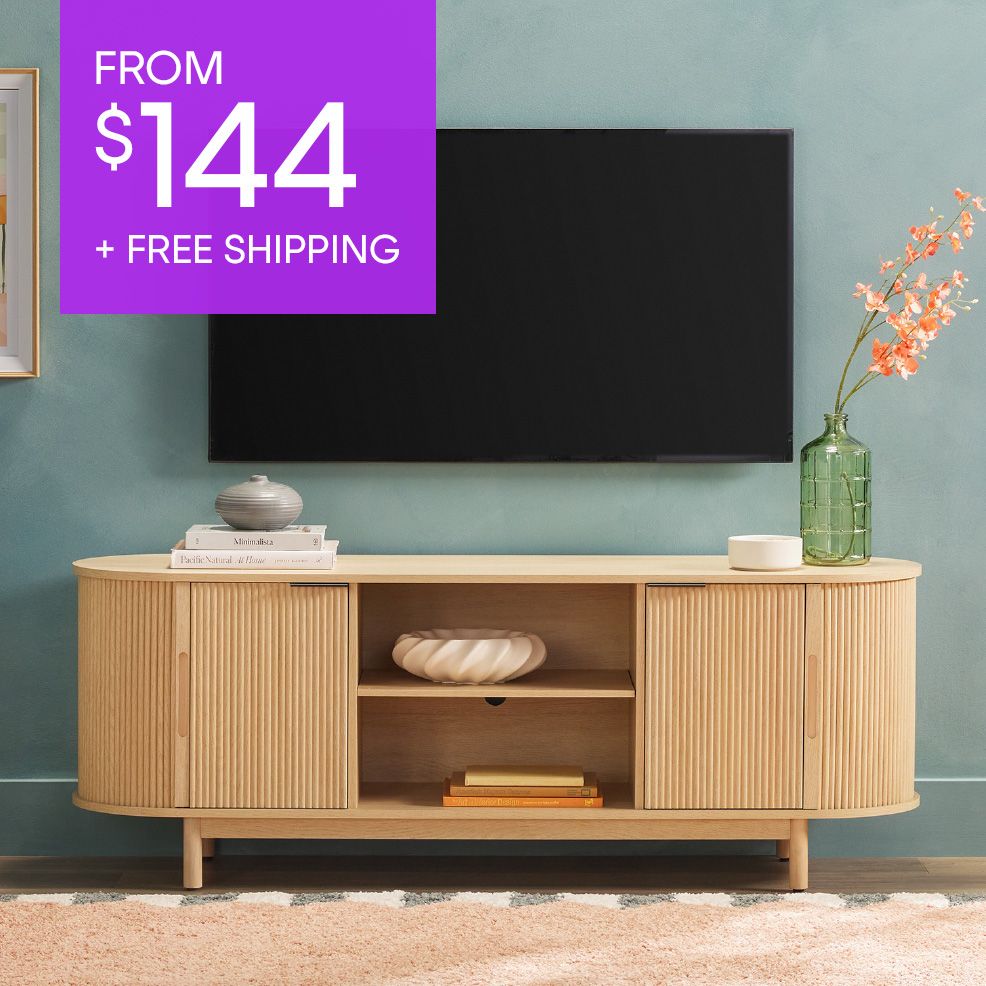 FROM $144 + FREE SHIPPING. A light wood TV stand with a TV mounted above it.
