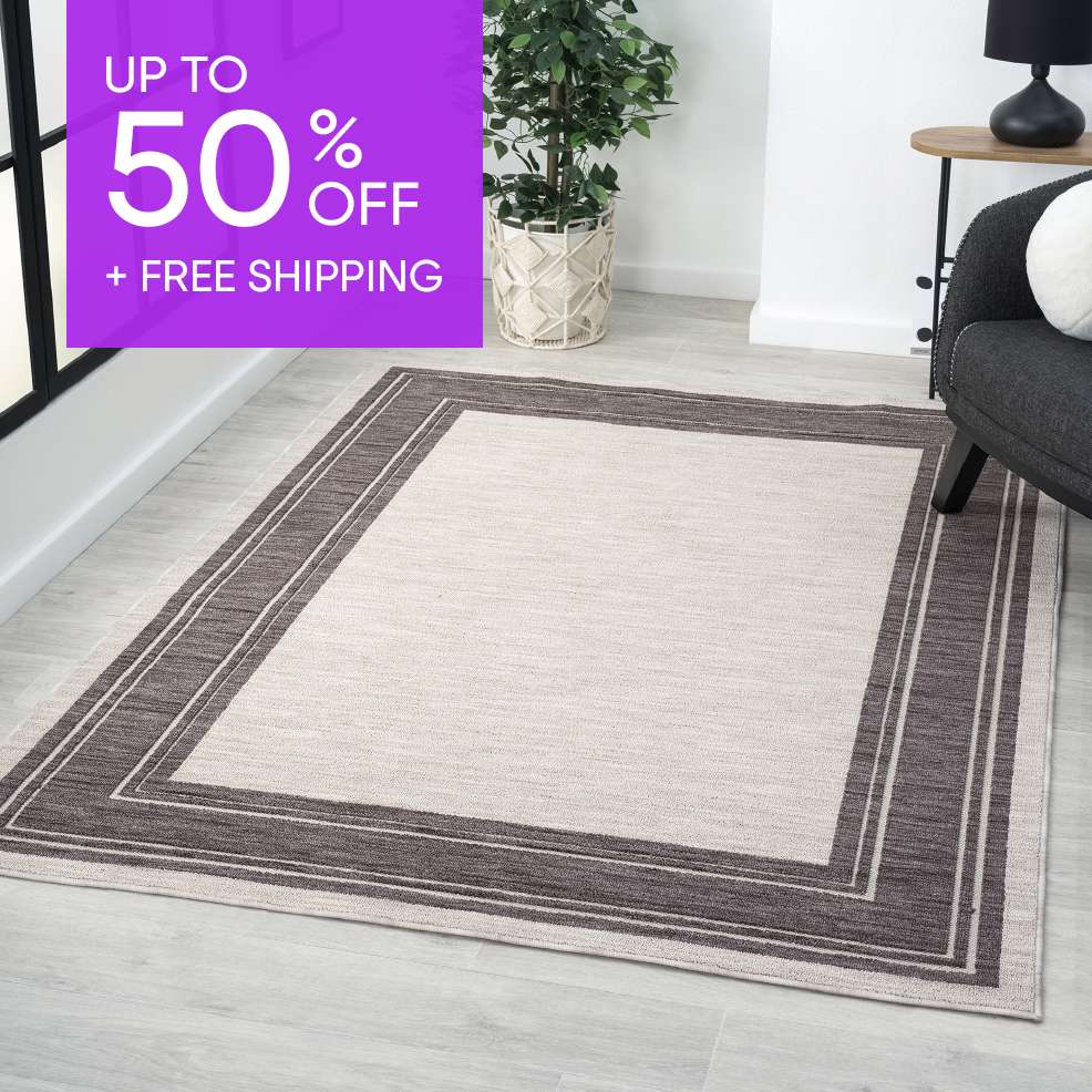 UP TO 50% OFF + FREE SHIPPING. A rectangular rug with a dark border on a light floor.
