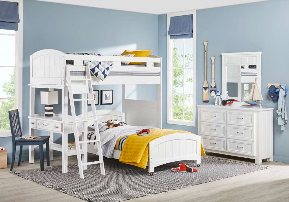 White bunk bed with a desk, dresser, and blue chair in a bedroom.
